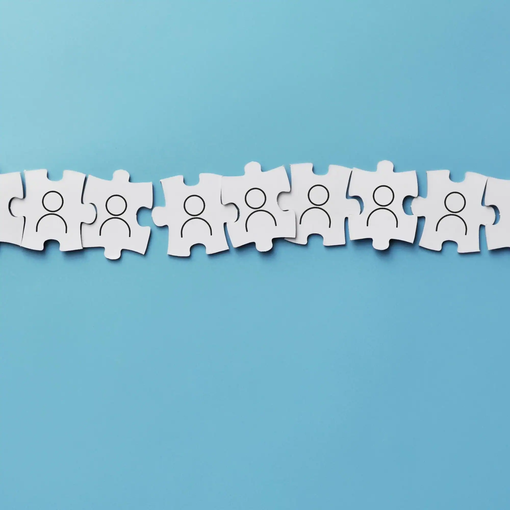 Puzzle pieces with stick figure people on them to represent teamwork.