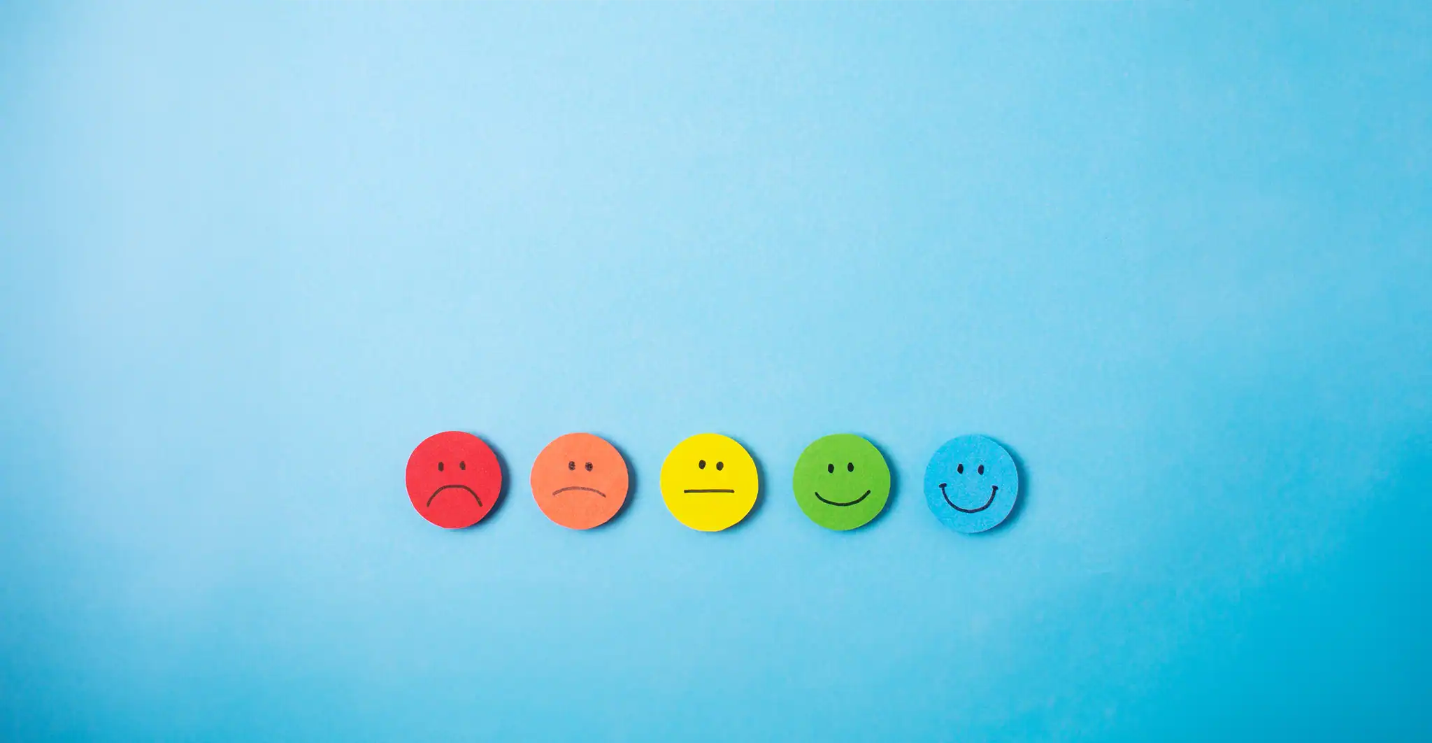 Blue background with multi-coloured faces with different emotions
