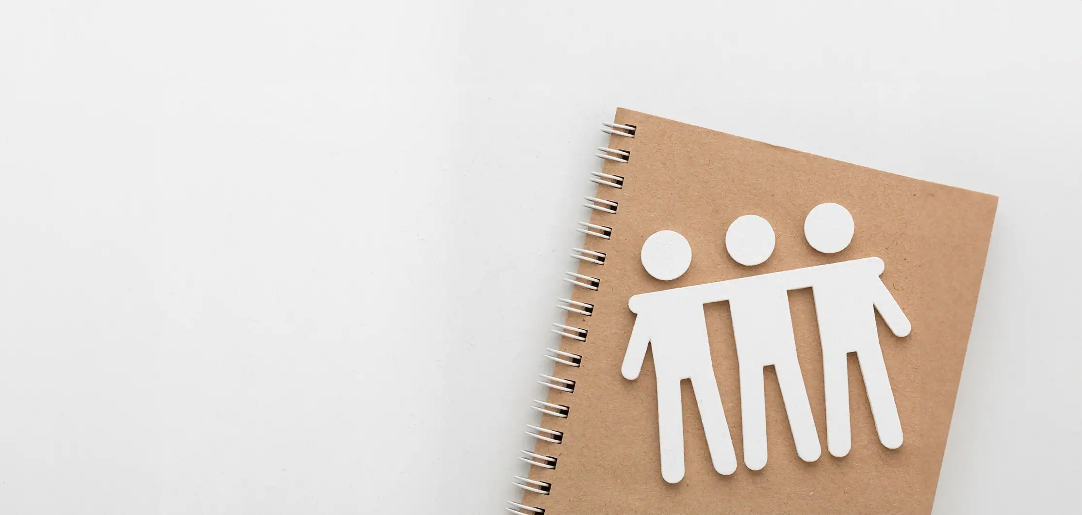 Paper cut-out figures on a notebook symbolising Community Living Association's history of standing together.