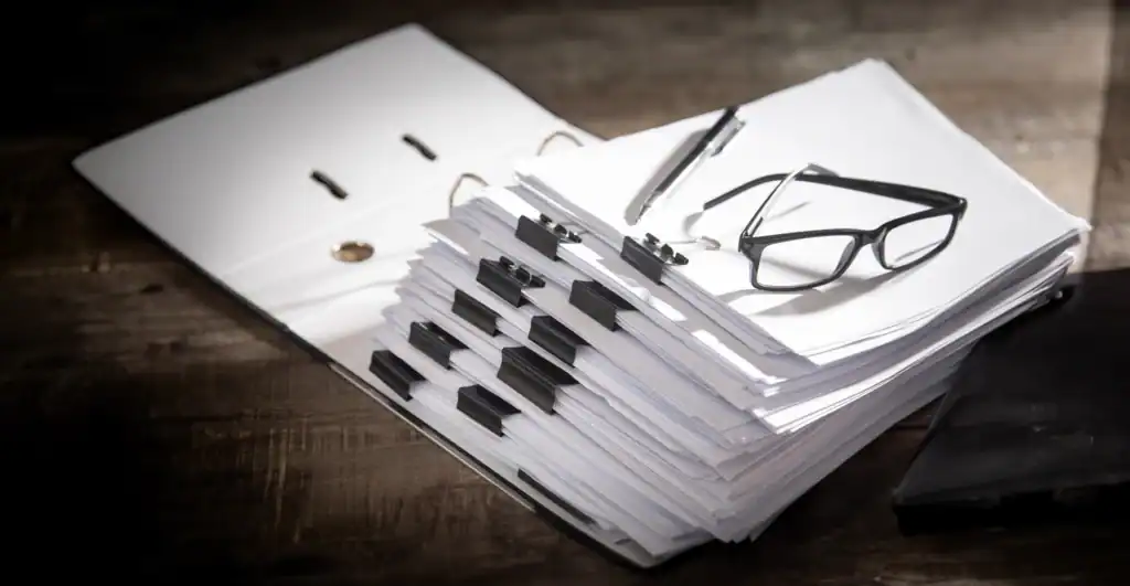 Printed policy and procedure documents with glasses, representing governance and compliance information