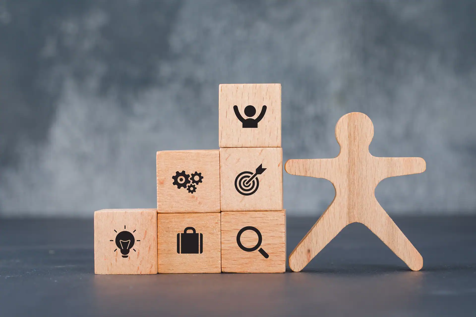 Wooden figure next to blocks showing employment, skills and training icons