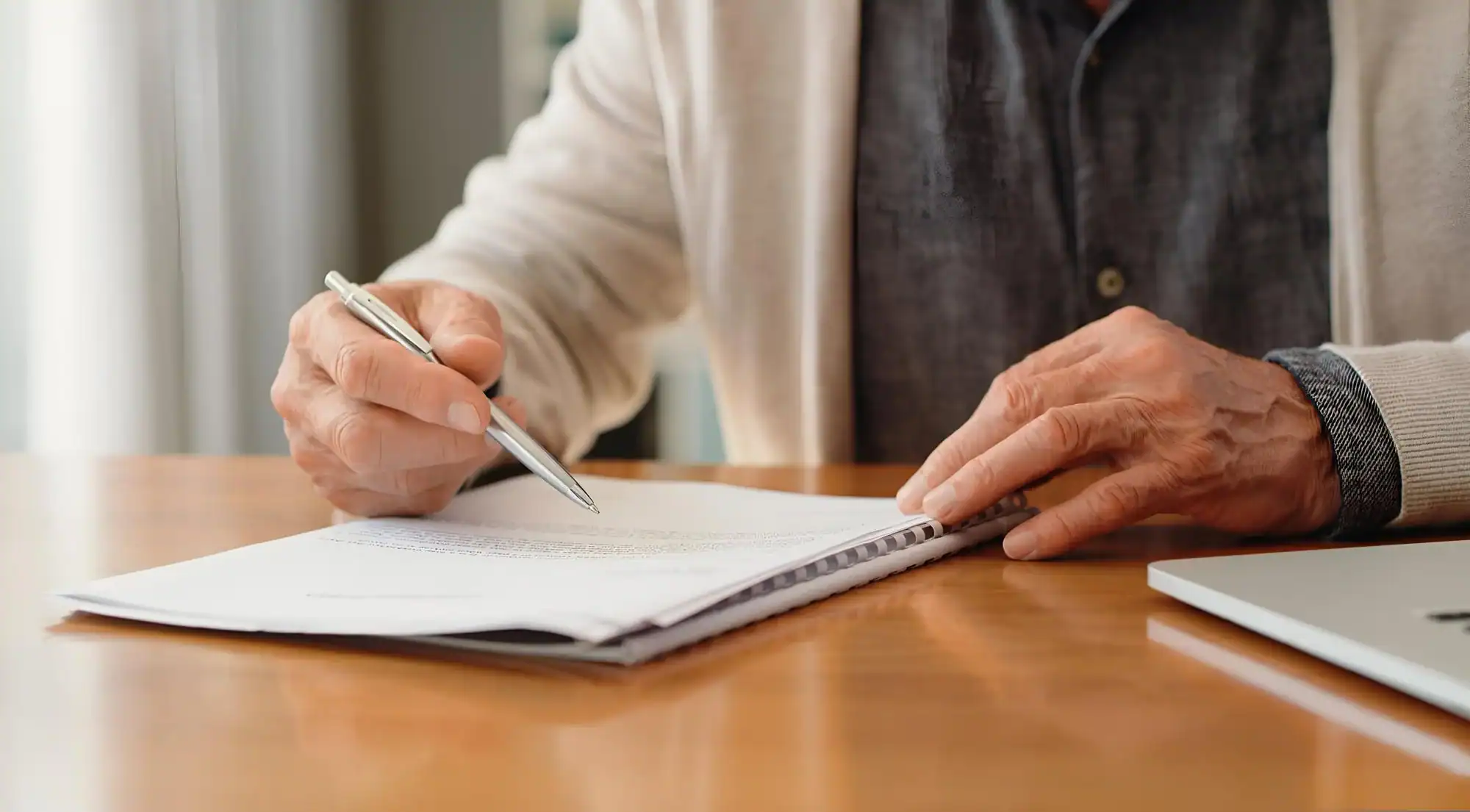 Older person reviewing and signing paperwork at home.