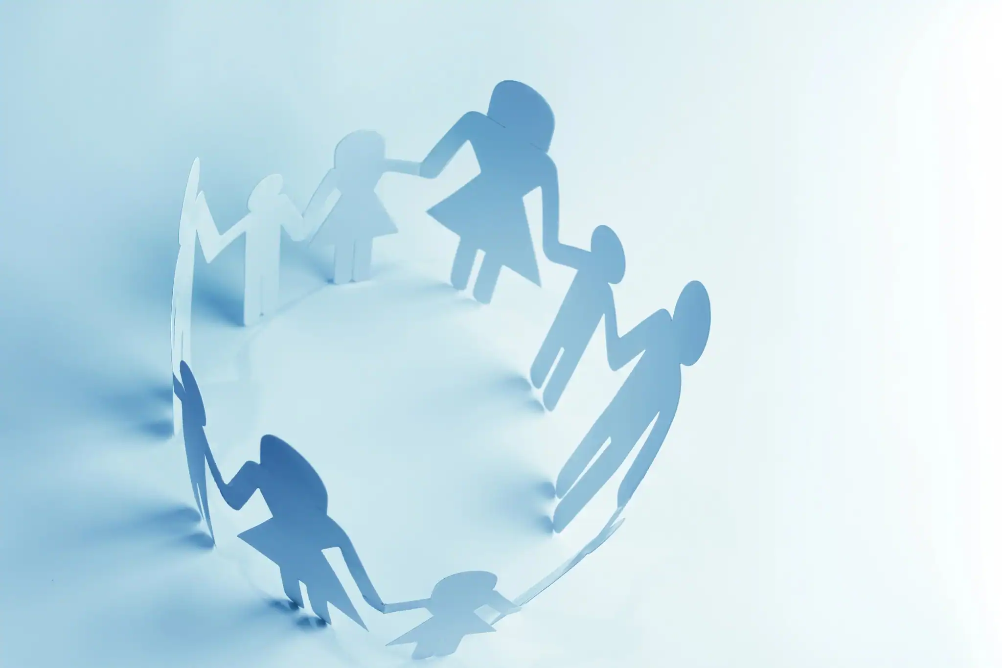 Paper cut-out people holding hands in a circle, representing connection, family support and community care.