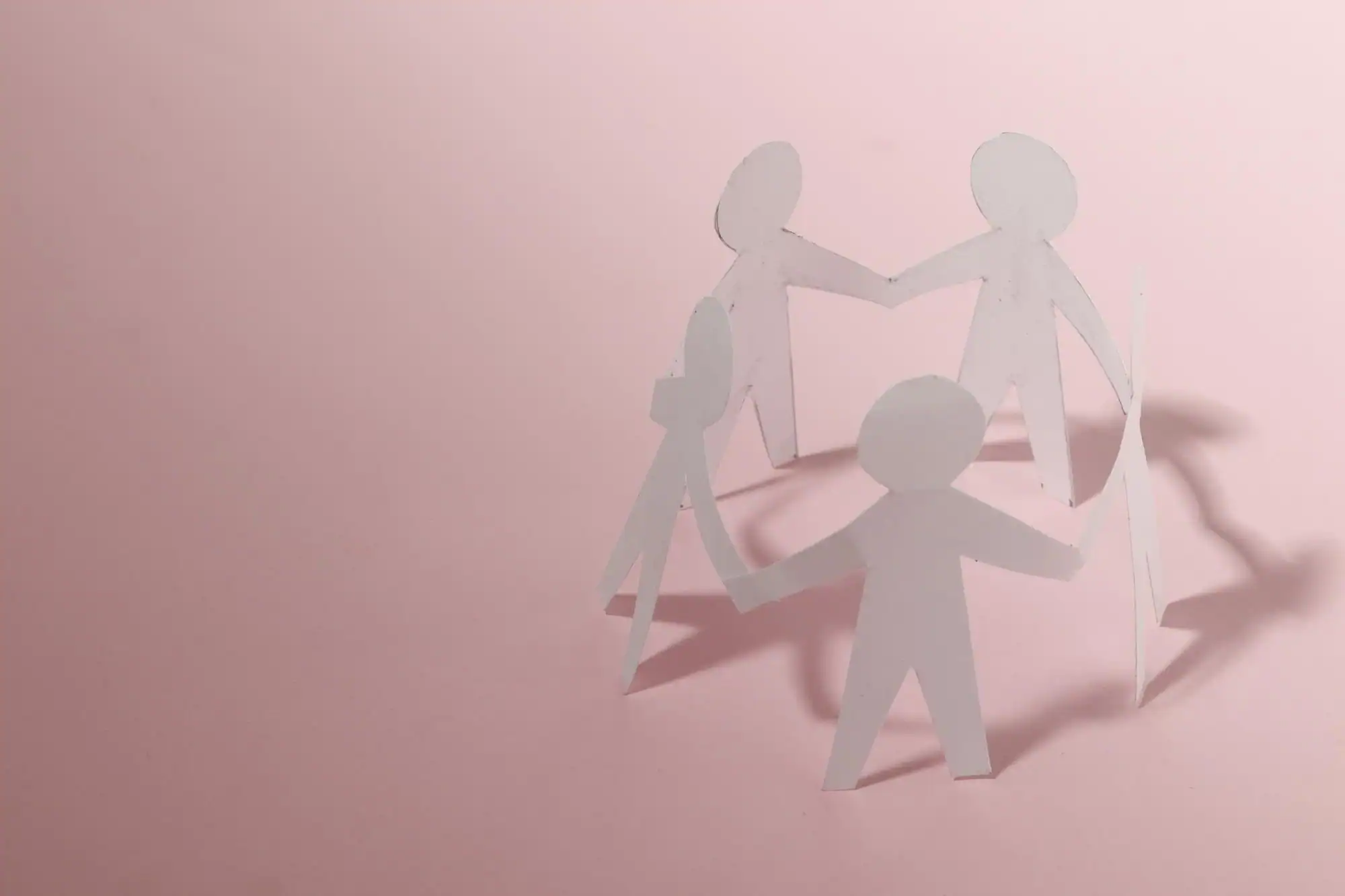 Paper cut-out people holding hands in a circle, representing connection, family support and community care.